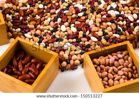 Mixed beans on a white background with individual beans in a wood box.