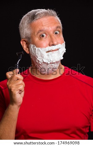 Handsome middle age man with shave cream on a black background.