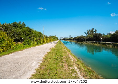 Long straight single lane rural road along a canal.