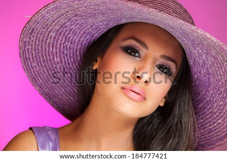 Beautiful young woman wearing a purple hat on a purple background.