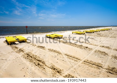Gulf coast beach in Gulfport, Mississippi with lounge chairs along the shoreline.