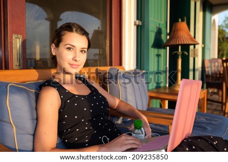 Beautiful girl with a laptop computer in the patio of a home.