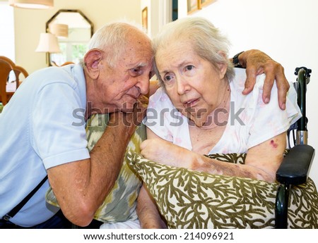 Elderly eighty plus year old woman in a wheel chair in a home setting with her husband.