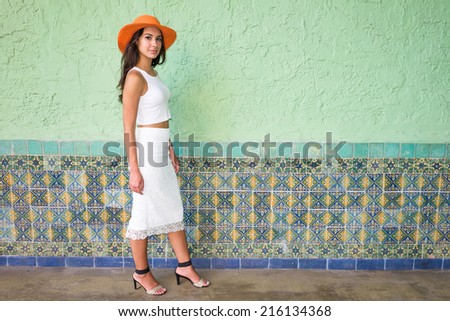 Beautiful young woman wearing a hat in a outdoor courtyard setting.