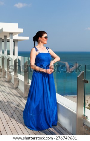 Beautiful middle age woman enjoying the sights of Miami Beach from a balcony.