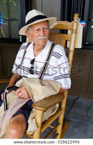 Elderly eighty plus year old man sitting on a rocking chair.