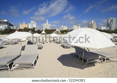 Lounge Chairs and Umbrellas in Miami\'s South Beach with Art Deco Hotels and Condos in the background.