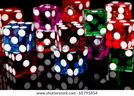 Colorful pairs of casino gaming/gambling dice isolated on a black background with reflection.