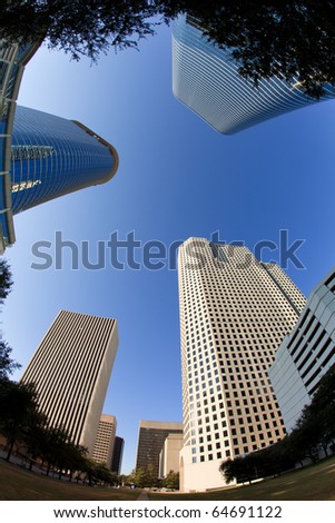 Upward fish eye view of tall skyscrapers against a blue sky in the downtown business area of Houston, Texas.