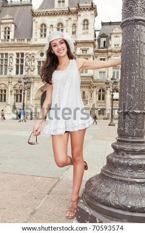 Beautiful multicultural young woman in a fashion pose in a typical Paris plaza with historical architecture in the background.