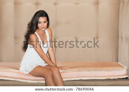 Beautiful young woman sitting on a large art deco sofa in a popular South Beach hotel in Miami Beach.