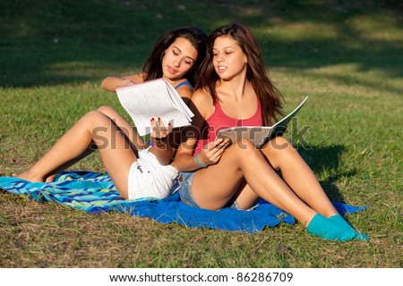 Pretty young female college students studying outdoors on a college campus.