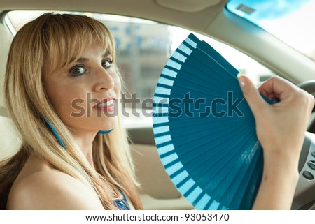 Attractive woman in a car with a hand fan.