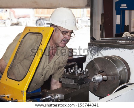 Industrial area. The mechanic works at the lathe.