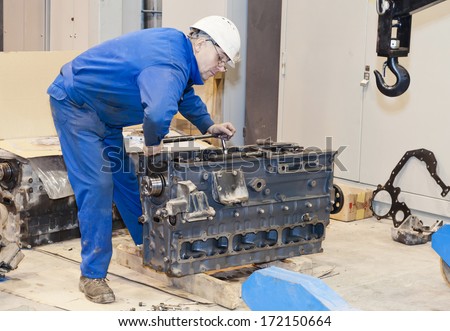 worker in protective clothes repairs the automobile mechanism