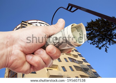 Man\'s Hand with notes of US dollars against the Residential building