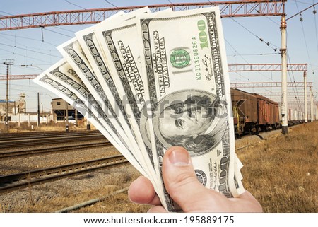 Man\'s Hand with notes of US dollars against the railroad