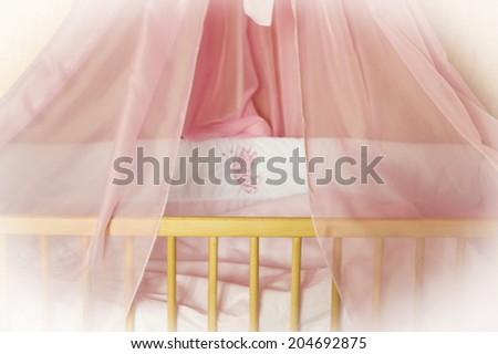 Children's wooden bed with pink bed linen on a white background