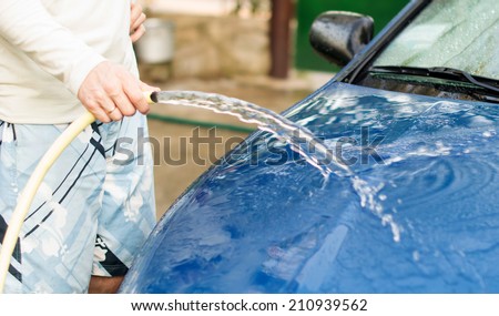 The process of washing cars with a hose with water in the yard