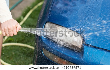 The process of washing cars headlights with a hose with water in the yard