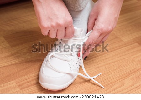 Process of clothing of white sports sneakers against a floor from a laminate
