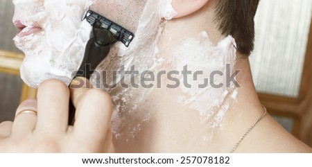 The process of shaving the face with a razor in the bathroom