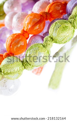 Fashion accessory: mother-of-pearl beads encased in colorful lace. White background.