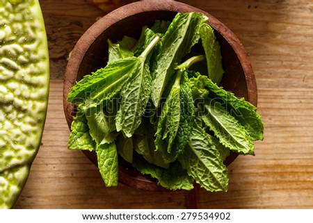 Scent of ingredients: mint leaves in wooden bowl on rustic wooden background.