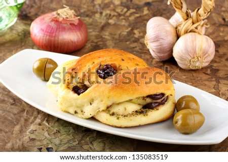 Bread seasoned with olive and oregano on complex background