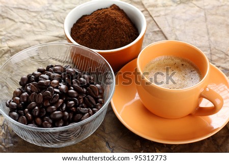 Cup of coffee with foam and coffee beans and ground coffee