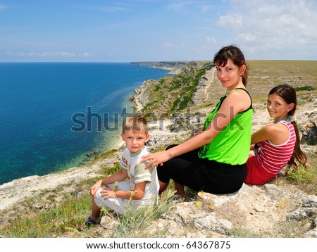 Mother and children sitting on the edge of a cliff at the seaside