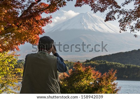 MOUNT FUJI - NOVEMBER 7: A man photographs Mount Fuji through fall foliage November 7, 2012 in Mount Fuji, JP. Viewing of seasonal foliage has been a popular past time in Japan for centuries.