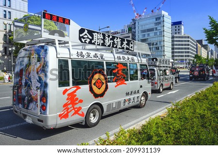 OSAKA, JAPAN - MAY 4, 2014: A caravan of Uyoku dantai vans drives through Osaka. The right wing groups are well known for propaganda vehicles which broadcast nationalistic slogans via loudspeaker.