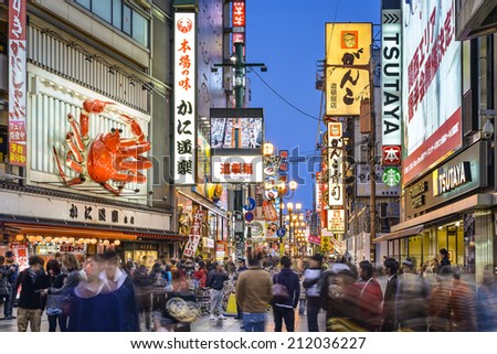 OSAKA, JAPAN - NOVEMBER 25, 2012: Crowds walk below the signs of Dotonbori. With a history reaching back to 1612, the district is now one of Osaka\'s primary tourist destinations.