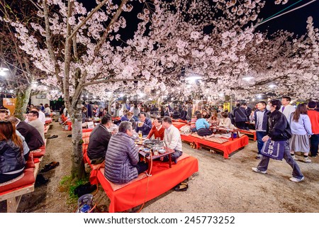 KYOTO, JAPAN - APRIL 3, 2014: Crowds enjoy the spring cherry blossoms by partaking in seasonal nighttime Hanami festivals in Maruyama Park.