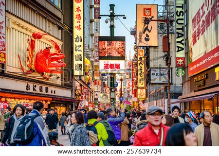 OSAKA, JAPAN - NOVEMBER 25, 2012: Crowds walk below the signs of Dotonbori. With a history reaching back to 1612, the district is now one of Osaka\'s primary tourist destinations.