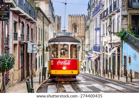 LISBON, PORTUGAL - SEPTEMBER 12, 2014: A tram passes the Lisbon Cathedral. The historic trams are a popular attraction.