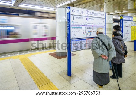 TOKYO, JAPAN - JANUARY 3, 2013: Riders view a subway map as a train approaches at Suitengumae Station.  The station is on the Tokyo Metro Hanzomon Line.