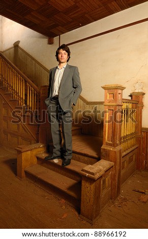 Man in suit on the stairs of an old vintage house.