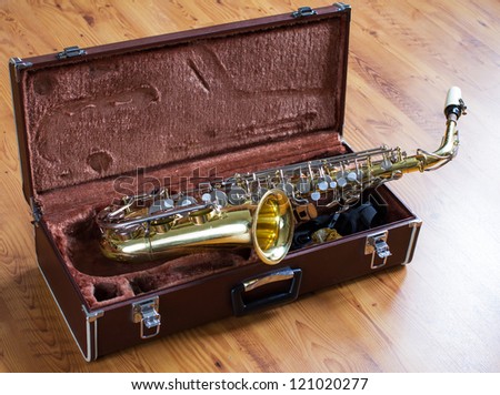 Saxophone with case on wood floor