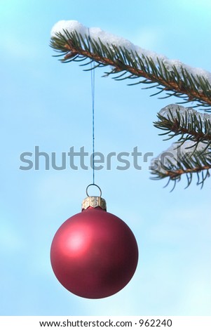 red christmas ball hanging on a snow covered tree. Focus on the ball.