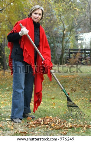 middle aged woman raking the leaves.