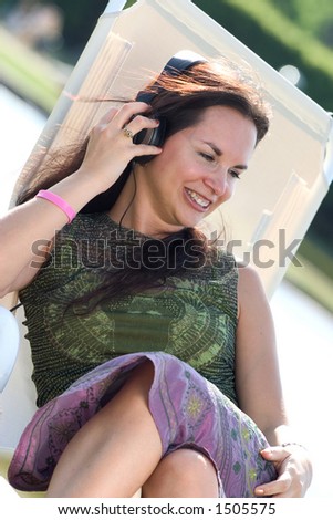 Woman reclining on a deck-chair and listening to music.