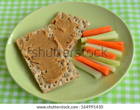 Peanut butter on whole grain crackers with fresh celery and carrot sticks