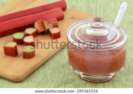 Rhubarb jam with raw rhubarb on bamboo cutting board