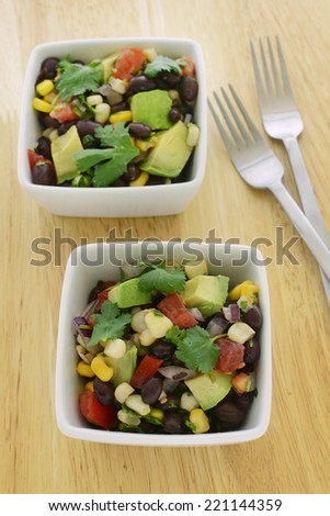 Black bean salad with avocado, corn, tomato, red onion and cilantro in vertical format