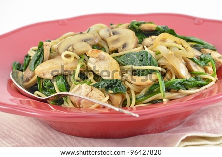 Mediterranean Chicken and Spinach Pasta dinner in coral serving bowl on white background