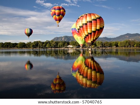 Colorful balloons are reflected in Prospect Lake during Colorado Springs Balloon Classic.