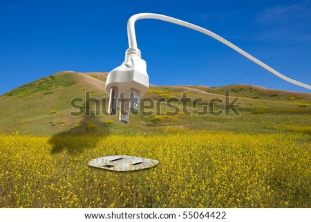 Clean renewable bio energy concept: large white power cord arching across a blue sky and diving down into an electrical plug set into a field of bio fuel mustard crops.