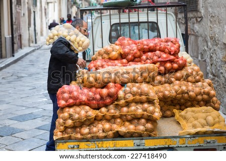 PALERMO, ITALY - OCTOBER 23, 2014: Farmer carrying bag of potatoes on Ballaro farmer\'s market on streets of old Palermo city center, around Plaza Carmine. It is oldest of Palermo\'s Arabic markets.